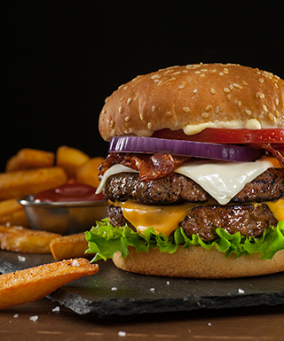 A burger with all fixings and some french fries.